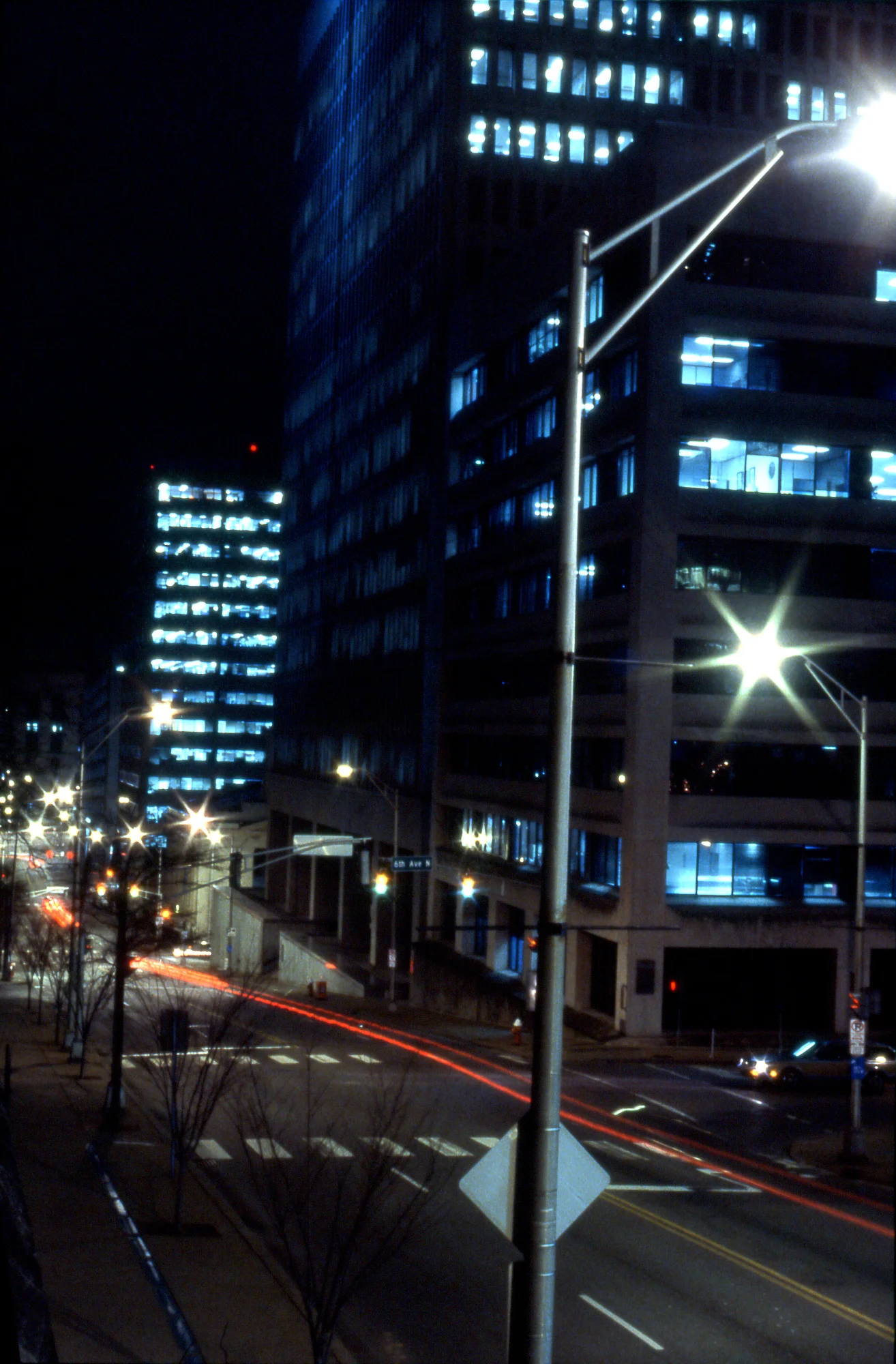 Downtown Nashville at night with bright windows and long red vehicle light trails.