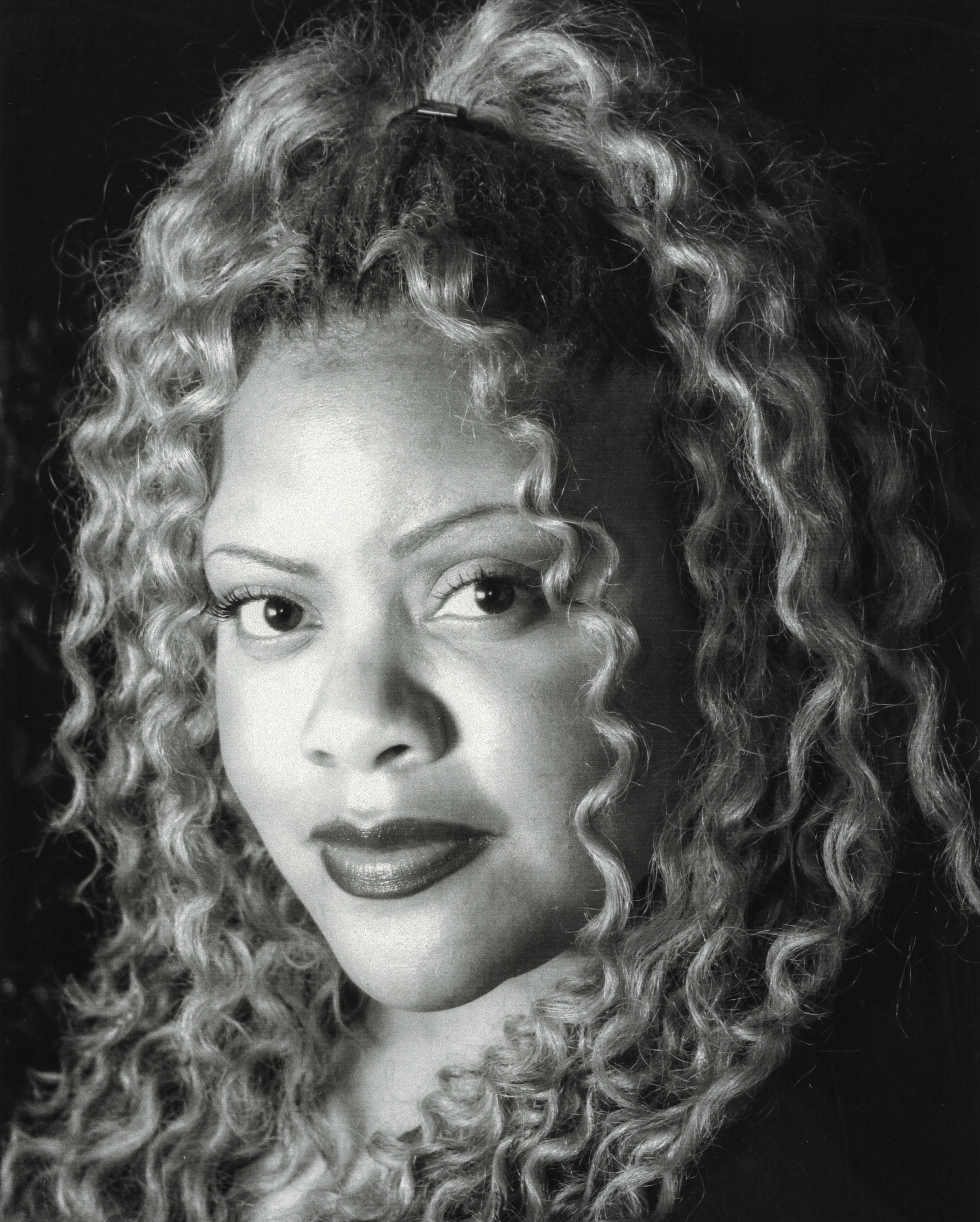 Black-and-white close portrait of a woman with curled hair.