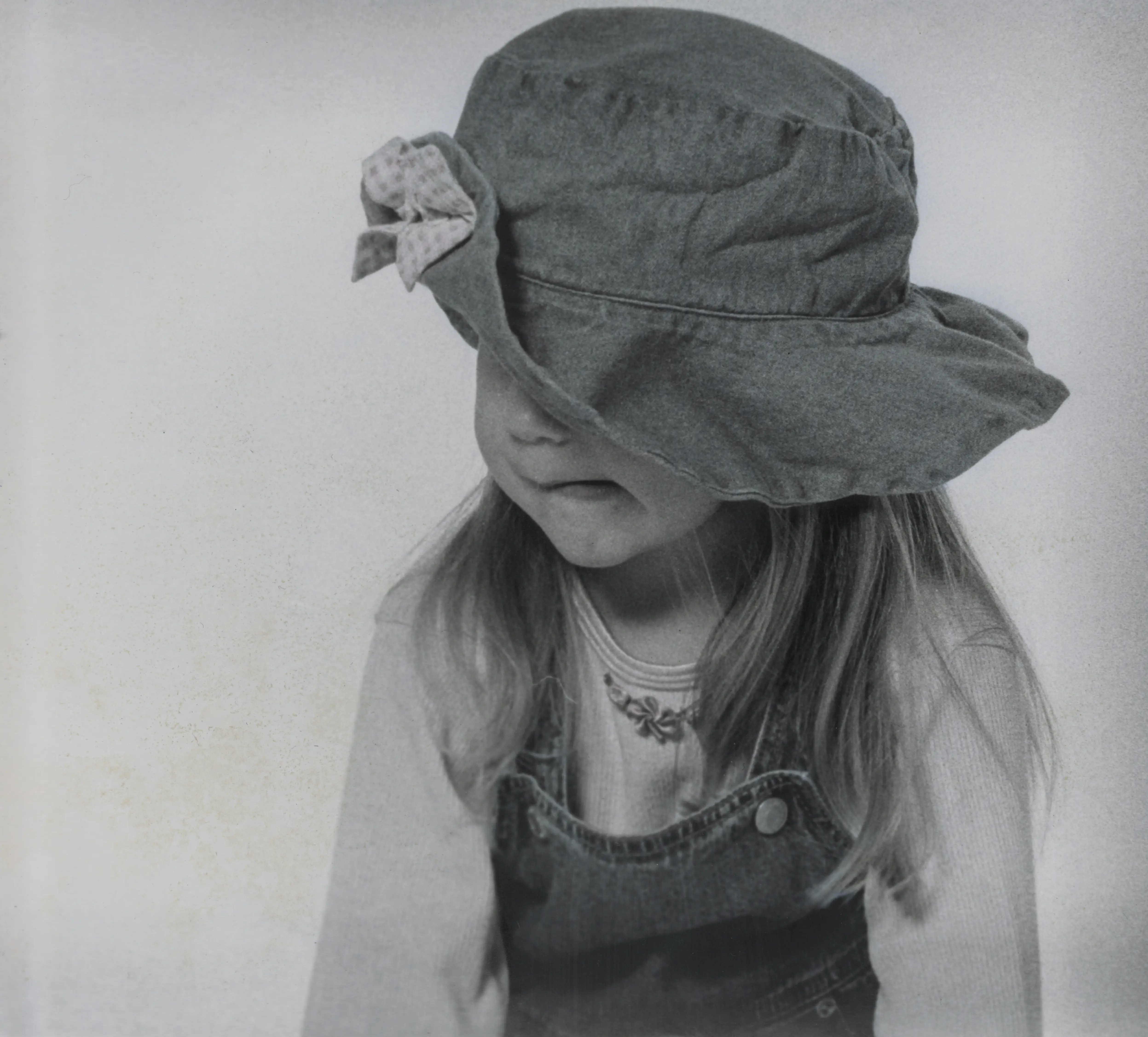 A young girl wearing an oversized hat that falls low across her face.